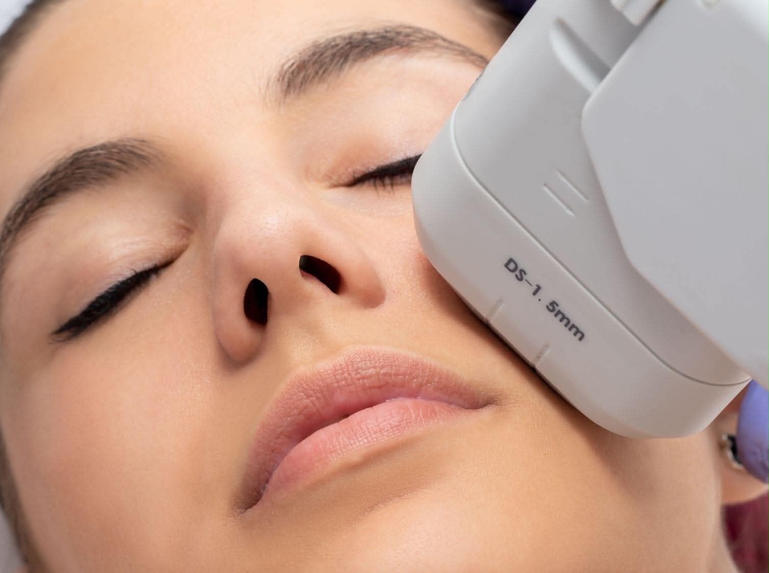 Close-up of an ultrasound probe on the cheek during a facial scan
